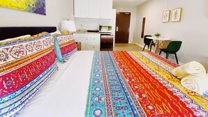 A hotel room with a large bed, a desk, a chair, a small kitchen area, and a dining table. - Comfortable SoBe Studio | Balcony | Free Beach Chairs & More (Miami Beach)
