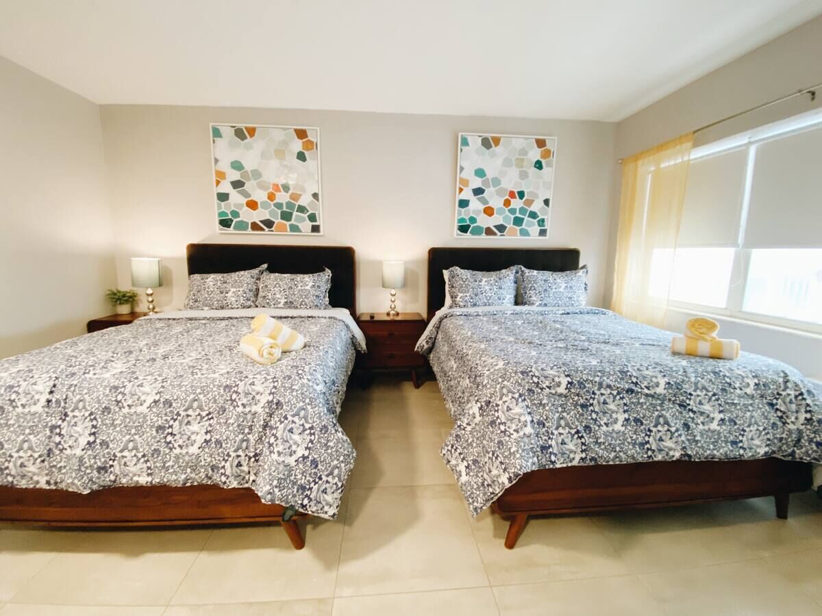 A double bed room with two nightstands, each with a lamp and a small table.