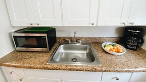 A kitchen with a stainless steel sink, a microwave, and a coffee maker on the countertop.