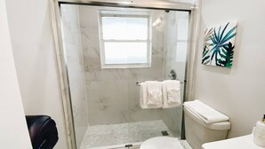 A modern bathroom with a glass-enclosed shower, a toilet, and a sink.