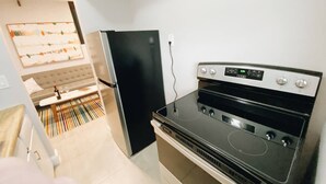 A compact kitchen with a black refrigerator, a stove, and a microwave.