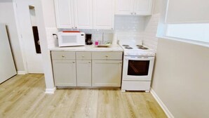 A compact kitchen with white cabinets, a microwave, a stove, and a coffee maker. - Accessible South Beach Unit w/ Free Perks (Miami Beach)