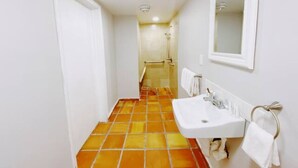A narrow bathroom with a tiled floor, a white sink, and a mirror on the wall. - Accessible South Beach Unit w/ Free Perks (Miami Beach)