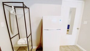 A compact room with a white wardrobe, a metal shelf unit, and a white refrigerator. - Accessible South Beach Unit w/ Free Perks (Miami Beach)