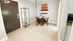 A compact living space with a kitchenette, a dining area with a table and chairs, and a door leading to another room. - Spacious Unit | Free Beach Chairs | Near Ocean (Miami Beach)