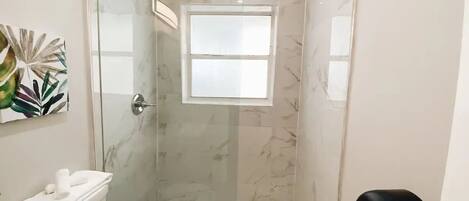 Un baño pequeño con ducha, inodoro y lavamanos.