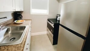 A compact kitchen with a stainless steel sink, a black countertop, and a refrigerator. - Spacious Unit | Free Beach Chairs | Near Ocean (Miami Beach)