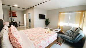 A modern hotel room with a large bed, a sofa, a TV, and a dining area in the background. - Spacious Unit | Free Beach Chairs | Near Ocean (Miami Beach)