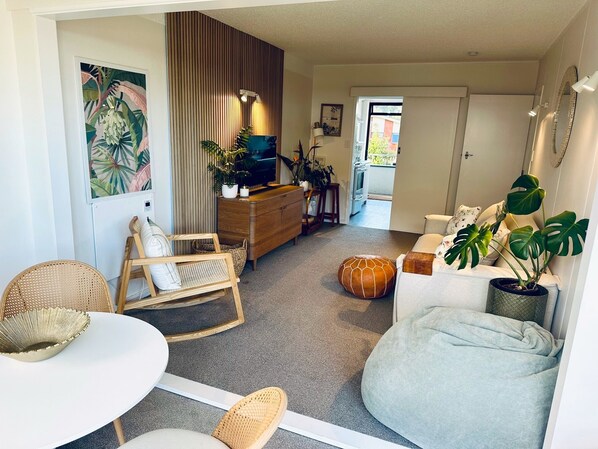 Ein gemütliches Wohnzimmer mit Sofa, Couchtisch, Fernseher und einem Essbereich mit Stühlen und Tisch.