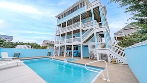 A multi-story building with a pool area, including a staircase and a deck with lounge chairs. - Accessible Semi-Soundfront: Pool, Hot Tub, Game Rm, Elevator, Boat Ramp, Linens (Rodanthe)