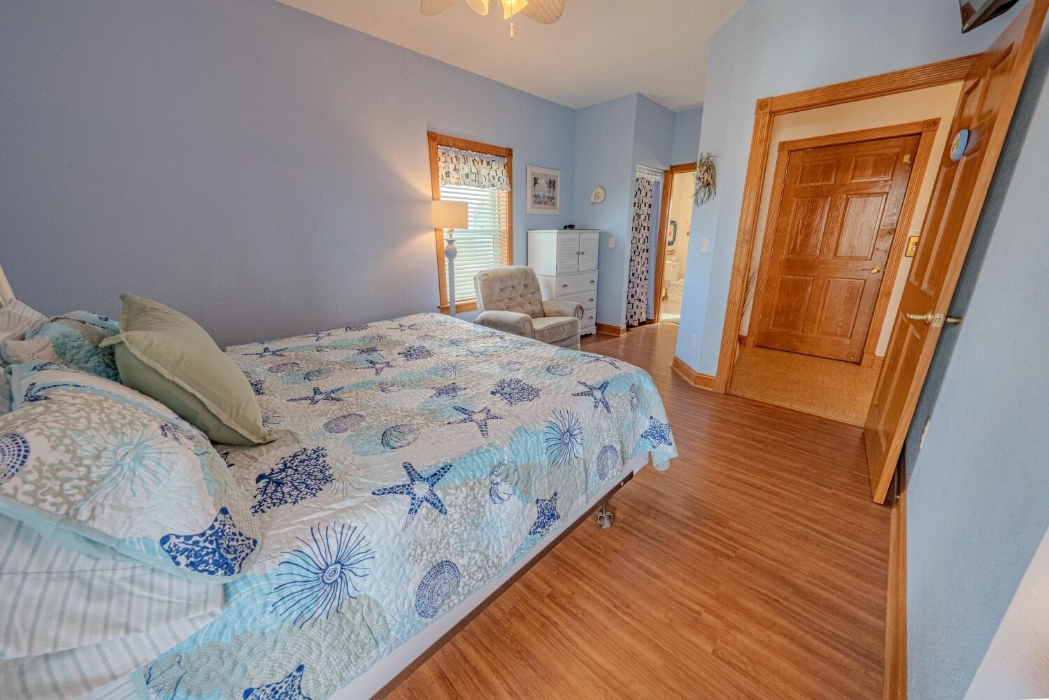 Ein Schlafzimmer mit einem Bett, einem Sessel, einem Schminktisch und einer Tür.