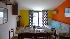 A dining area with a table set for four, a sofa, and a window with curtains. - Green Bay B16 - Three-room apartment on the 2ndFloor (Pineto)