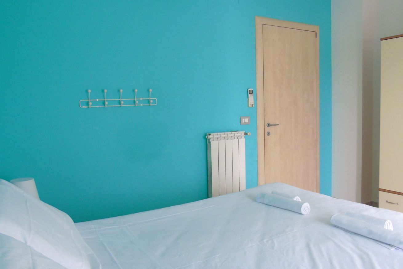 A room with a bed, a radiator, a door, and a wall-mounted hook.