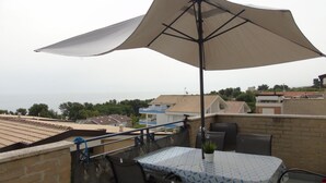 A rooftop terrace with a table and chairs, a large umbrella, and a view of the sea. - Green Bay B16 - Three-room apartment on the 2ndFloor (Pineto)