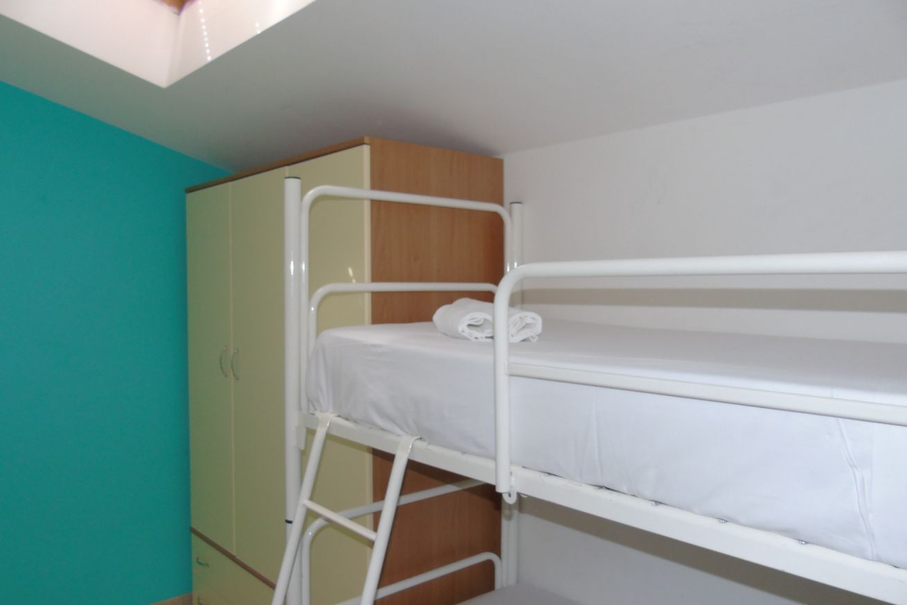 A bunk bed with a ladder, a wardrobe, and a teal wall.