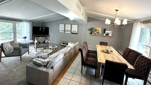 Een moderne woonkamer met een bank, salontafel en een eettafel met stoelen.