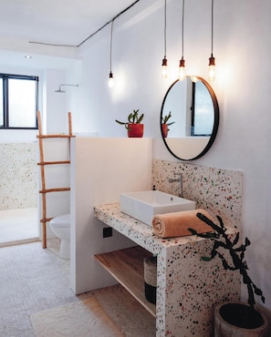 A modern bathroom with a freestanding sink, a mirror, and a wooden ladder.