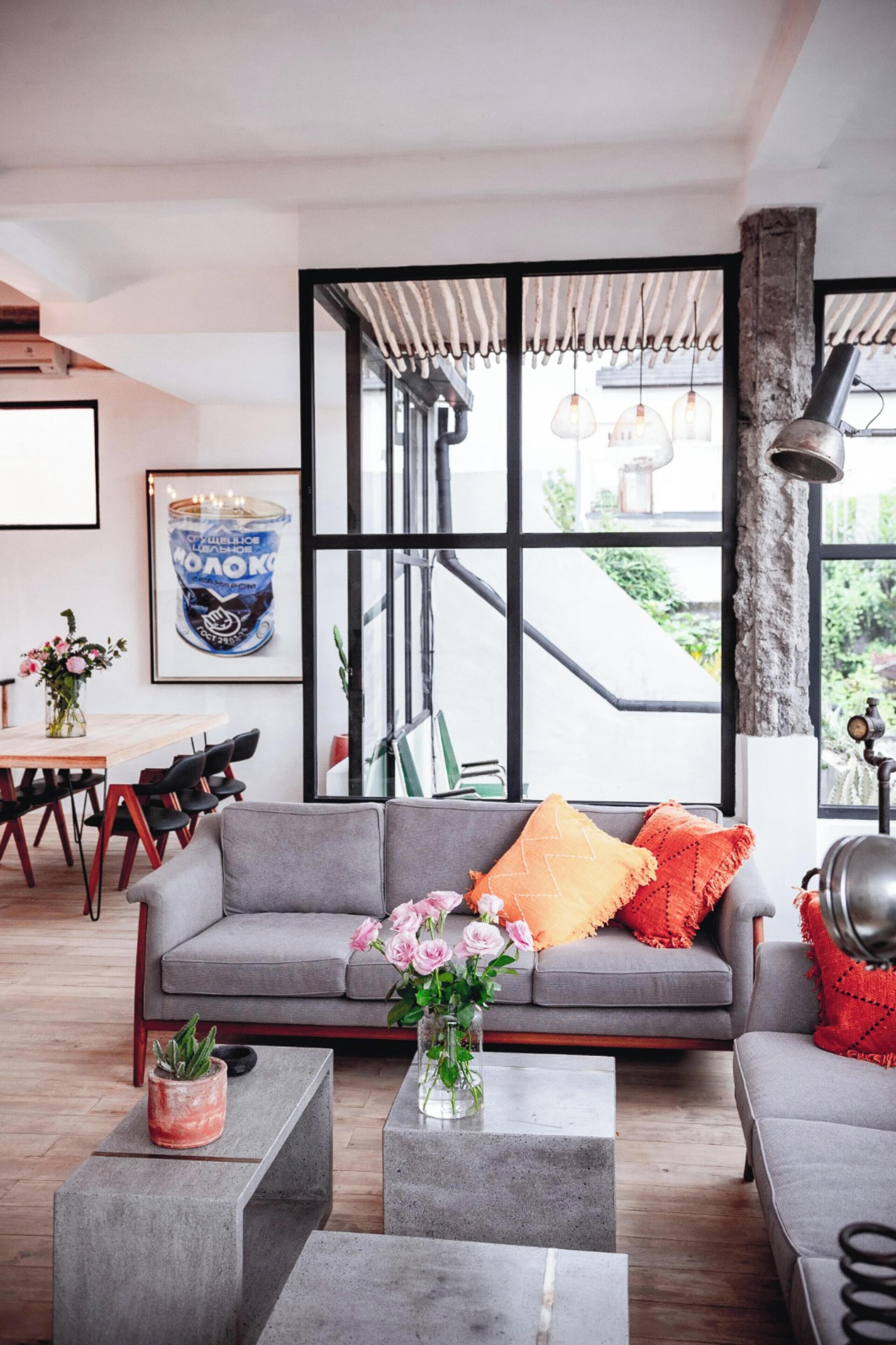 Una sala de estar moderna con un sofá gris, una mesa de centro y un comedor con una mesa y sillas.