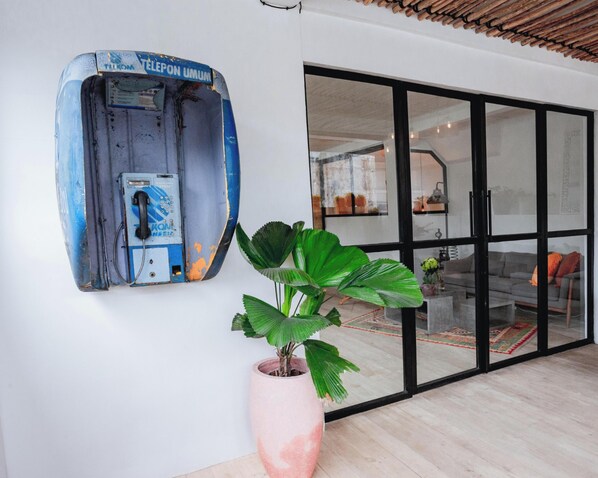 A room with a large window, a potted plant, and a blue object on the wall.