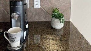 A kitchen with a coffee maker, a potted plant, and boxes of coffee on the shelf. - Entire Home in Edmonton South close to Airport with fenced private yard & deck (Edmonton)