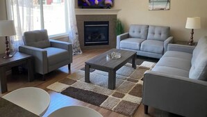 A living room with a fireplace, a television, and a sofa. - Entire Home in Edmonton South close to Airport with fenced private yard & deck (Edmonton)