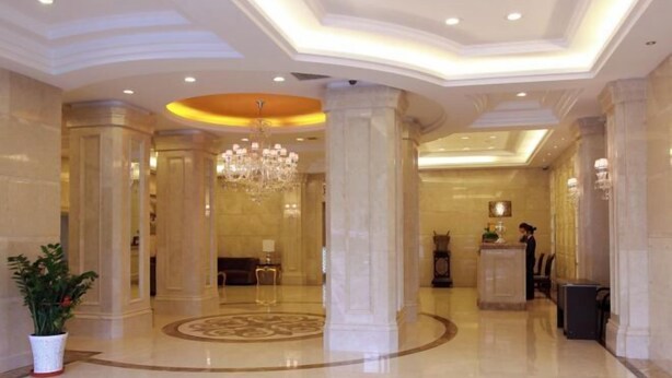A spacious lobby with marble flooring, a central chandelier, and a reception desk. - Wolff Hotel (Suifenhe)
