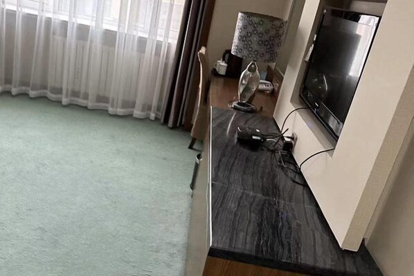 Une pièce avec un comptoir en marbre foncé, un téléviseur à écran plat fixé au mur, une lampe et une chaise.