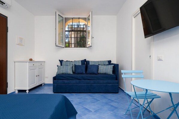 A compact room with a blue sofa, a small table, and a cabinet.