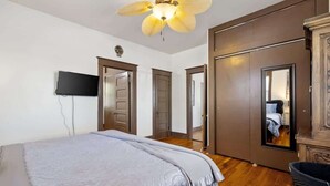 A bedroom with a bed, a ceiling fan, a television, and a wardrobe. - Historic 1919 Home | Walk to Downtown (Prescott)
