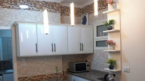 A compact kitchen with white cabinets, a gas stove, a microwave, and a coffee maker. - 1 bedroom apartment sleeping 2 people's only (Sharm Elshake)