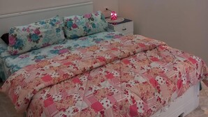 A bed with floral bedding, a bedside table with a lamp, and a nightstand. - 1 bedroom apartment sleeping 2 people's only (Sharm Elshake)