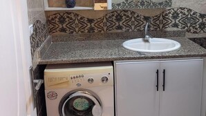 A compact kitchen with a built-in washing machine, a sink, and a mirror above the countertop. - 1 bedroom apartment sleeping 2 people's only (Sharm Elshake)