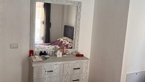 Un dormitorio con tocador, cama y un espejo grande.