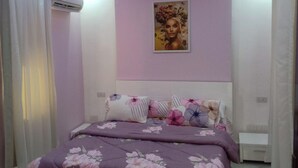 A bedroom with a bed, floral bedding, a wall-mounted air conditioner, and a framed picture above the bed. - 2Bed Sea View Apartment - Sleeps 5 w Free Parking (Sharm El-Sheikh)
