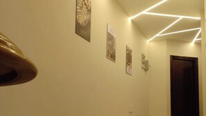 A hallway with a wooden handrail, a tiled floor, and wall-mounted light fixtures. - 2Bed Sea View Apartment - Sleeps 5 w Free Parking (Sharm El-Sheikh)