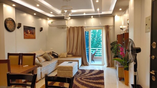 A modern living room with a sofa, dining table, chairs, and a fan. - 2Bed Sea View Apartment - Sleeps 5 w Free Parking (Sharm El-Sheikh)