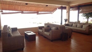A spacious living area with wicker furniture, a fan, and large windows. - Lubi Resort (Santander)