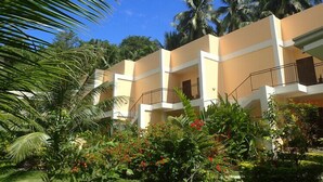 A hotel with multiple balconies, surrounded by lush greenery and palm trees. - Lubi Resort (Santander)