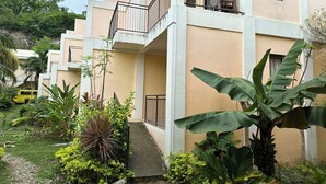 A multi-story building with a balcony, surrounded by lush greenery and a small garden area. - Lubi Resort (Santander)