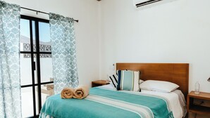 A bedroom with a bed, a nightstand, a bench, and a window with patterned curtains. - Charming 2-bedroom hotel with AC, WiFi in amazing Cerritos (Cerritos)