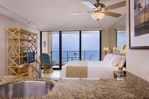 Ein modernes Hotelzimmer mit Balkon, einem Bett, einer Sitzecke und einer Küche mit Spüle.