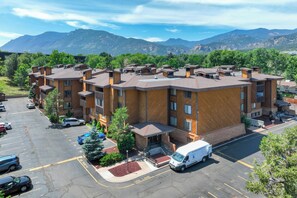 A multi-story hotel with a parking lot and a mountain backdrop. - Trailhead Terrace (Colorado Springs)