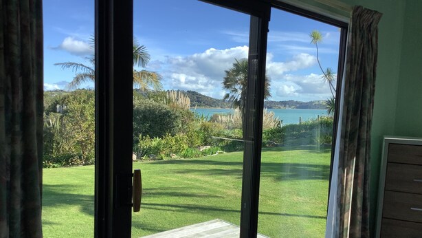 A room with a sliding glass door leading to a deck with a view of a grassy area and a body of water.
