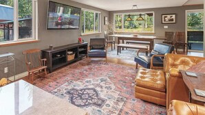 Una sala de estar con chimenea, un televisor grande y un comedor con vistas al exterior.