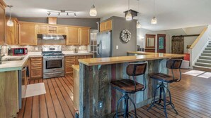 Una cocina con armarios de madera, una estufa de acero inoxidable y una isla de madera con taburetes de bar.