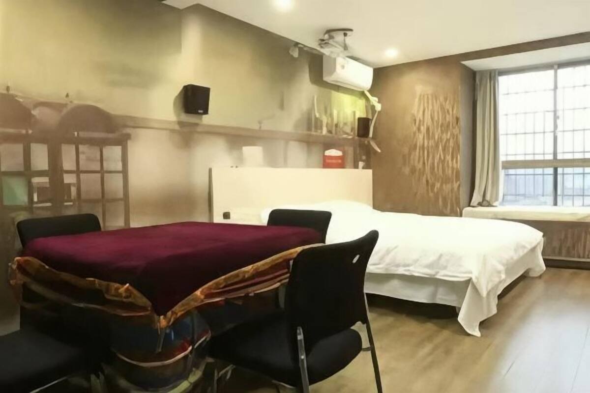 Une chambre dâhĂŽtel comprenant un lit, un bureau avec une chaise, une fenĂȘtre et un climatiseur fixĂ© au mur.