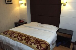 Een hotelkamer met een bed, nachtkastjes, lampen en een aan de muur hangend schilderij.