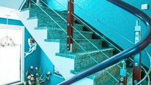 A staircase with a metal handrail, a wall with a textured finish, and a window with a light fixture. - Shengsi Yajing Homestay (Shengsi)