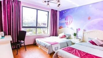 A bedroom with two beds, a desk, and a chair. There is a window with curtains, a wall mural of hot air balloons, and a chandelier.