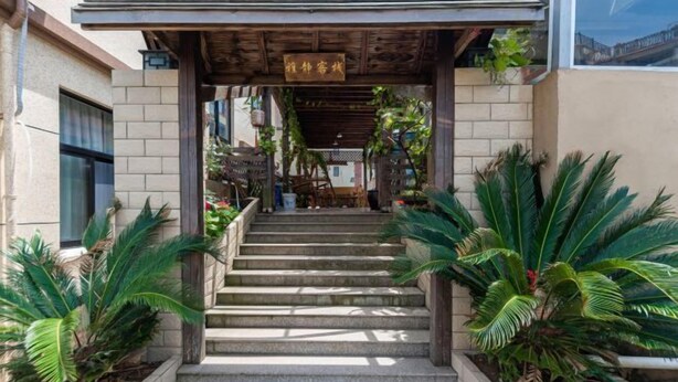 A building entrance with a wooden pergola, steps, and potted plants. - Shengsi Yajing Homestay (Shengsi)